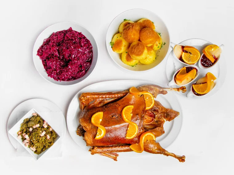 Fertig zubereitete Weihnachtsgans mit Orangenscheiben, dazu Rotkohl, Grünkohl, Klöße mit Bröselbutter und Williamsbirnen mit Preiselbeeren – alles aus dem Paket
